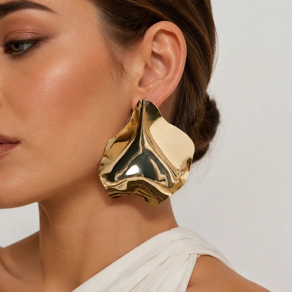 Sculptural gold-tone earrings worn by a model