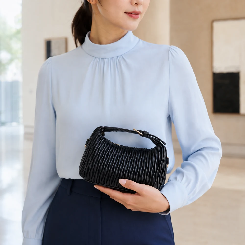 Black mini satchel with wavy quilted texture — model view Model carrying a black mini satchel with wavy quilted texture