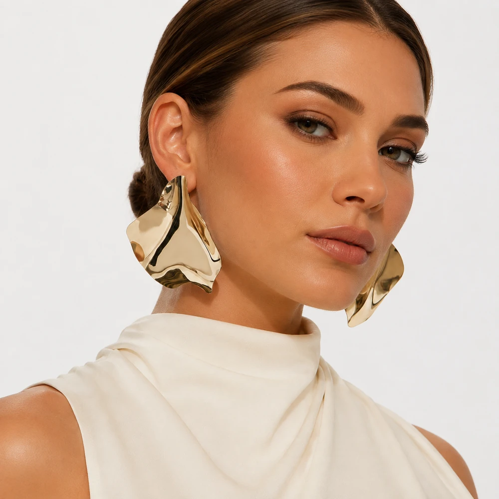 golden-foil-flakes-gold-statement-earrings-lifestyle-02 Oversized gold-tone sculptural stud earrings worn beside a light sleeveless top